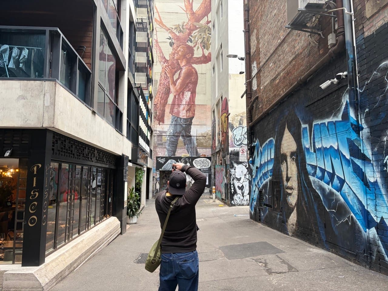 Ron shooting with his Sony A7CR in a Melbourne laneway with street art murals during a photography course