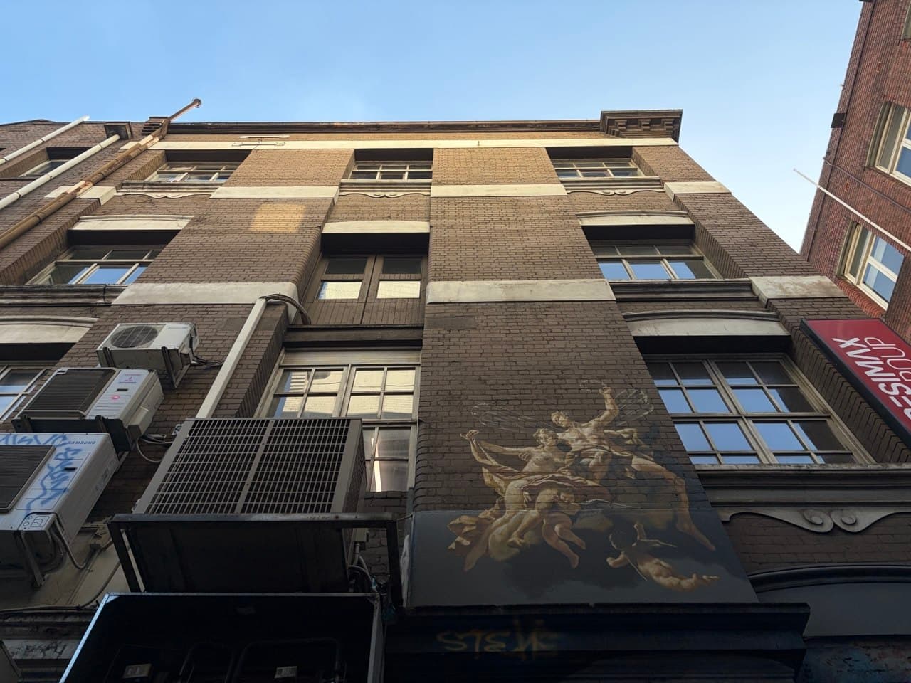 Looking up at a Melbourne CBD brick building with a painted classical mural during the photography course