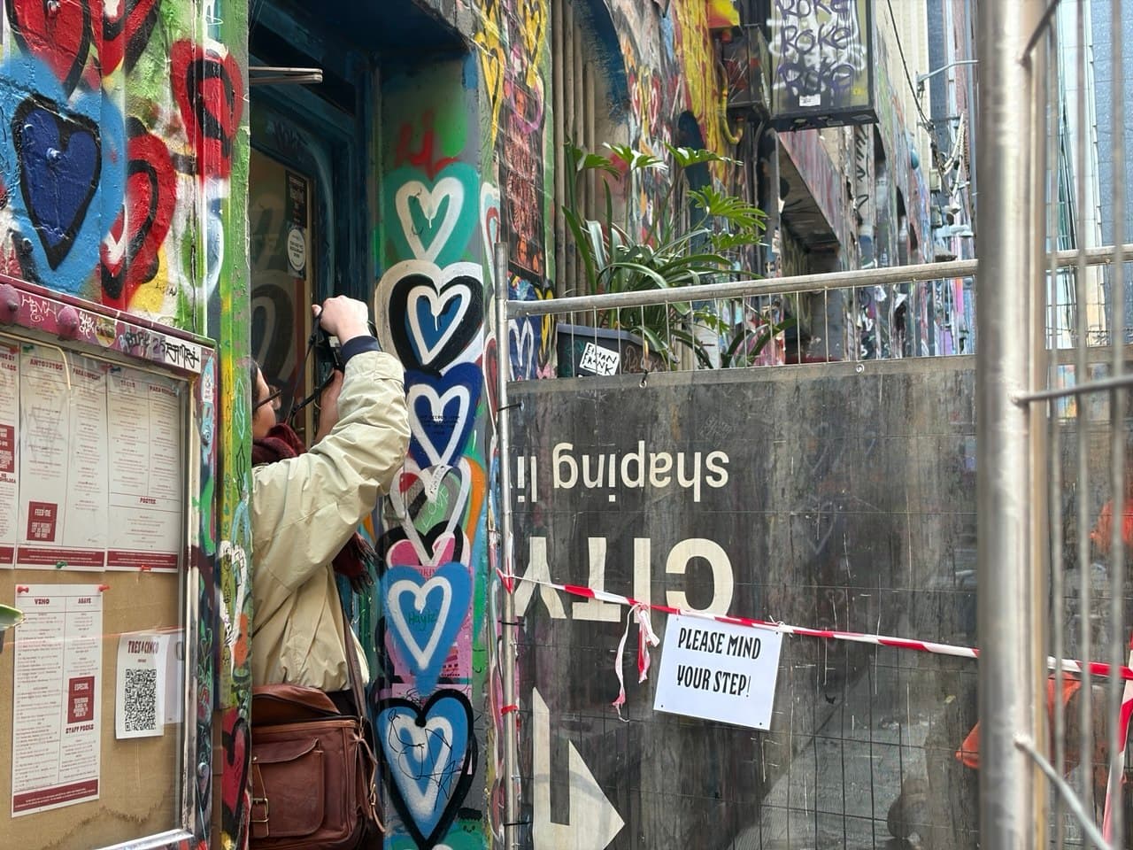Cosette photographing a street-art laneway in Melbourne CBD with painted hearts on the walls during the photography course