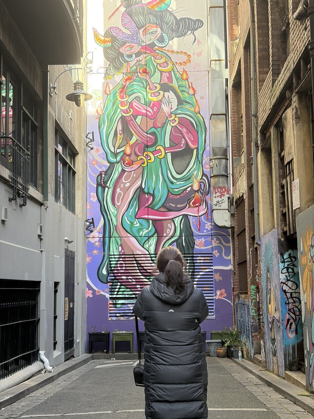 Penny standing in a Melbourne CBD laneway photographing a tall green-robed mural during the photography course