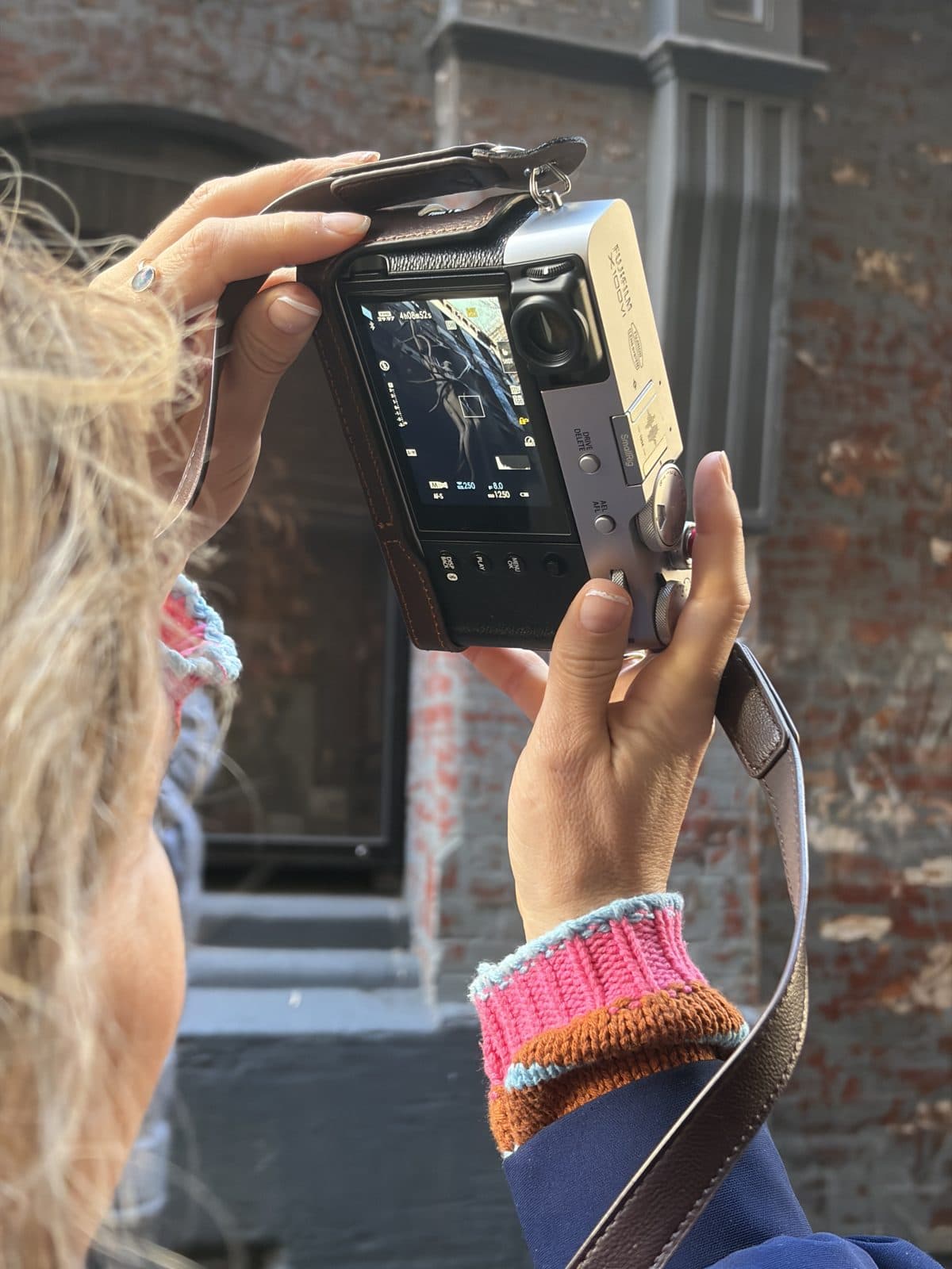 A Fujifilm X100VI held up to review a shot against a rusted brick wall during a Melbourne street photography course