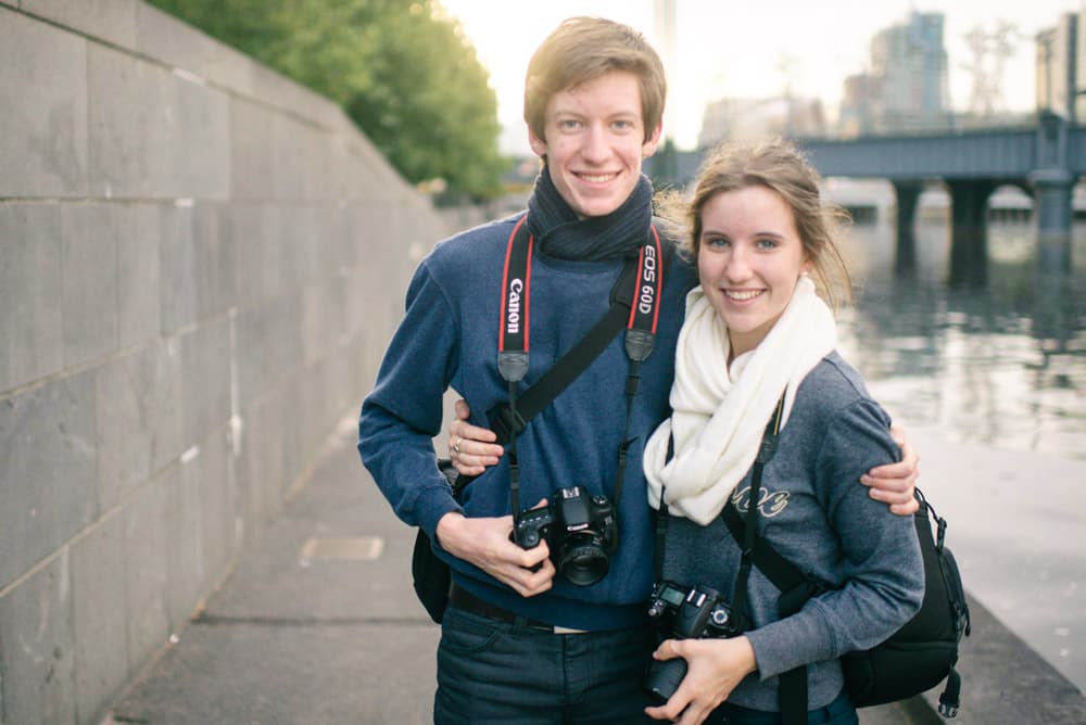 Couple smiling with cameras beside Yarra River during Melbourne photography course